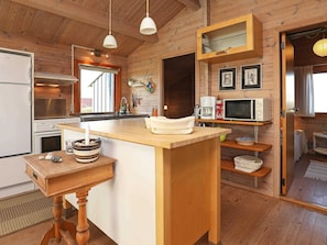 A wooden interior with a kitchen area, including a stove, microwave, and wooden counter.