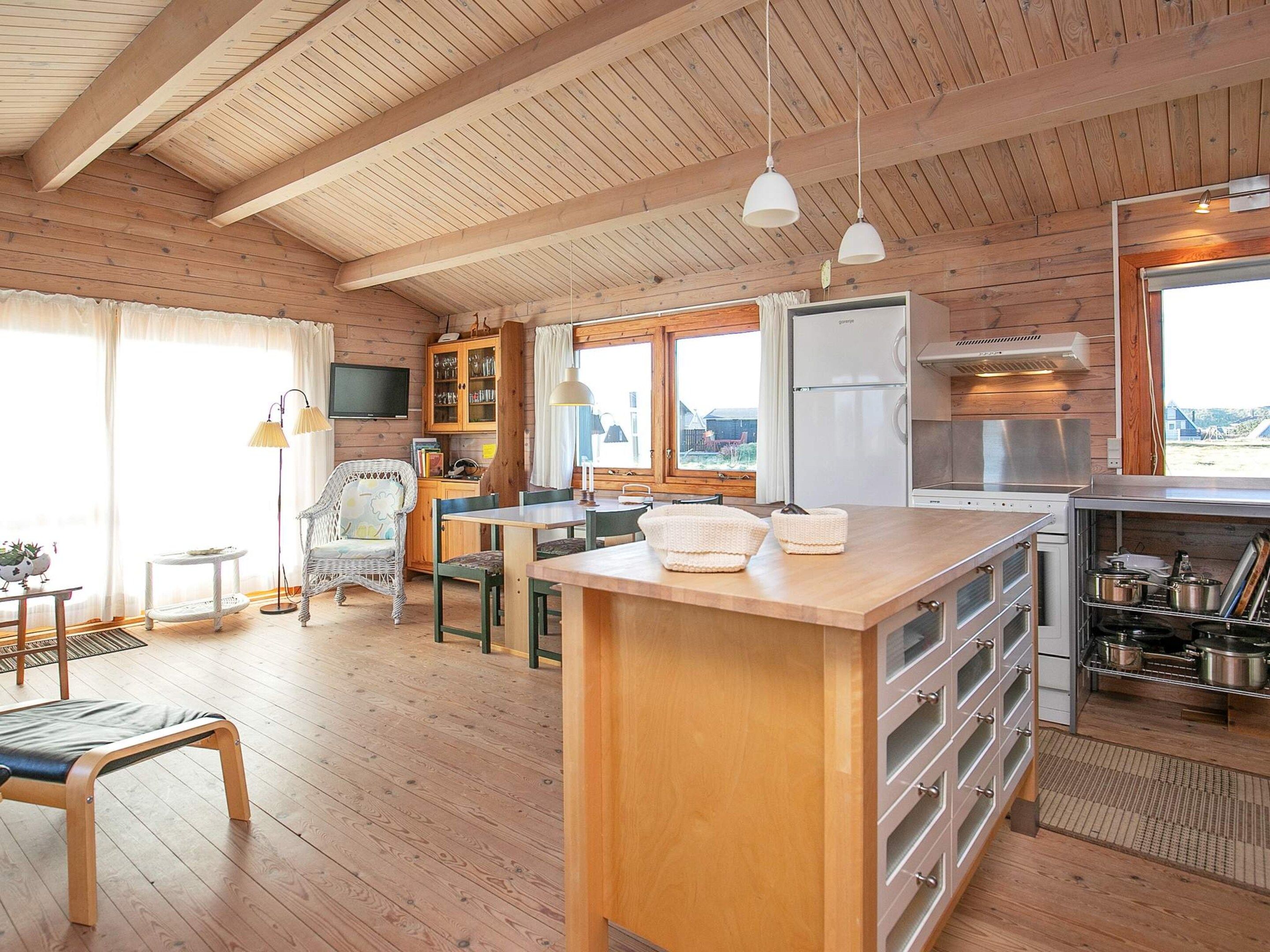 A wooden interior with a kitchen, dining area, and a large window.