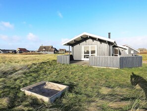 A modern house with a large window, a chimney, and a wooden deck. - 8 Person Holiday Home in Harboore (Harboore)