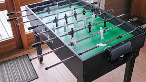 A foosball table in a room with wooden flooring and a window. - 8 Person Holiday Home in Harboore (Harboore)