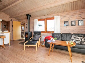 A cozy cabin interior with a fireplace, wooden walls, a sofa, and a dining area. - 8 Person Holiday Home in Harboore (Harboore)