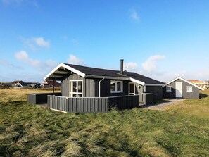A modern house with a large porch, a chimney, and a well-maintained lawn. - 8 Person Holiday Home in Harboore (Harboore)