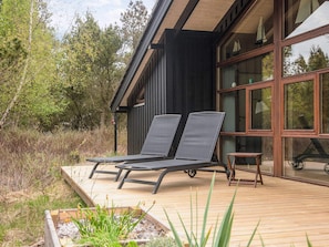 A modern house with a deck, two lounge chairs, and a small table. - 5 Star Holiday Home in Fjerritslev (Fjerritslev)