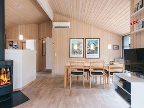 A modern interior with a dining area, wooden walls, and a fireplace. - 5 Star Holiday Home in Fjerritslev (Fjerritslev)