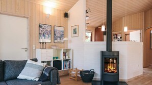 A cozy living room with a fireplace, wooden walls, a sofa, a coffee table, and a bookshelf. - 5 Star Holiday Home in Fjerritslev (Fjerritslev)