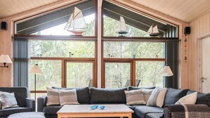 A cozy living room with a large window, wooden ceiling, and a sofa set. - 5 Star Holiday Home in Fjerritslev (Fjerritslev)
