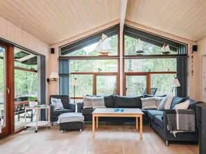A modern interior with a large window, a sofa, a table, and a small cart.