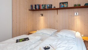 A bedroom with two beds, wooden panel walls, a bookshelf, and a framed picture. - 5 Star Holiday Home in Fjerritslev (Fjerritslev)