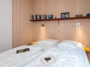 A bedroom with two beds, wooden panel walls, a bookshelf, and a framed picture. - 5 Star Holiday Home in Fjerritslev (Fjerritslev)