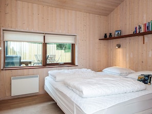 A room with a bed, a window, a bookshelf, and a radiator.