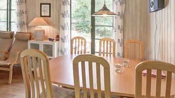 Un comedor con mesa y sillas de madera, una lámpara y vistas a través de una ventana.
