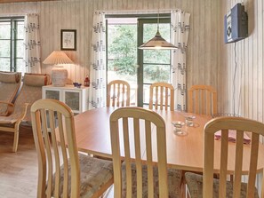 A dining area with a wooden table and chairs, a lamp, and a view through a window. - 6 Person Holiday Home in Nexo (Nexø)