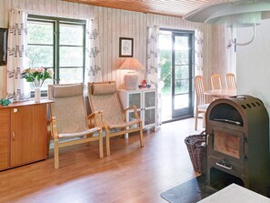 A cozy room with a wooden floor, a fireplace, a dining table with chairs, and a window with curtains. - 6 Person Holiday Home in Nexo (Nexø)