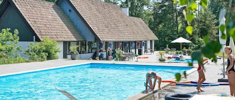 A swimming pool area with lounge chairs, a small building, and a picnic table.