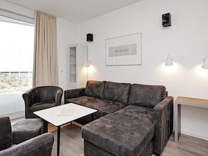 A modern living room with a sectional sofa, a small table, and a cabinet. - Holiday Home in Wendtorf (Wendtorf)