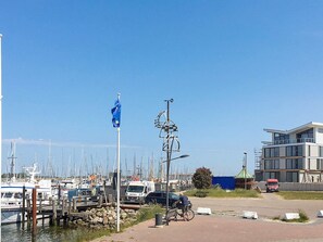 A marina with boats docked, a flagpole with a flag, and a modern building under construction. - Holiday Home in Wendtorf (Wendtorf)