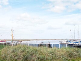 Un puerto deportivo con barcos amarrados, un primer plano con césped y un cielo nublado.