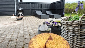 Un patio con una parrilla, mobiliario exterior y una cesta decorativa.