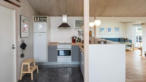 Una cocina moderna con una isla central, horno empotrado y campana extractora de acero inoxidable.