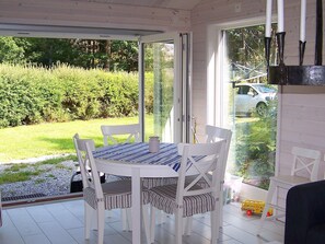 A covered patio with a table and chairs, a sliding glass door, and a view of a car and greenery outside. - Holiday Home in KÃ¥llekÃ¤rr (Kållekärr)