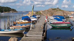 A marina with boats docked along a wooden pier, calm water, and a rocky shoreline in the background. - Holiday Home in KÃ¥llekÃ¤rr (Kållekärr)
