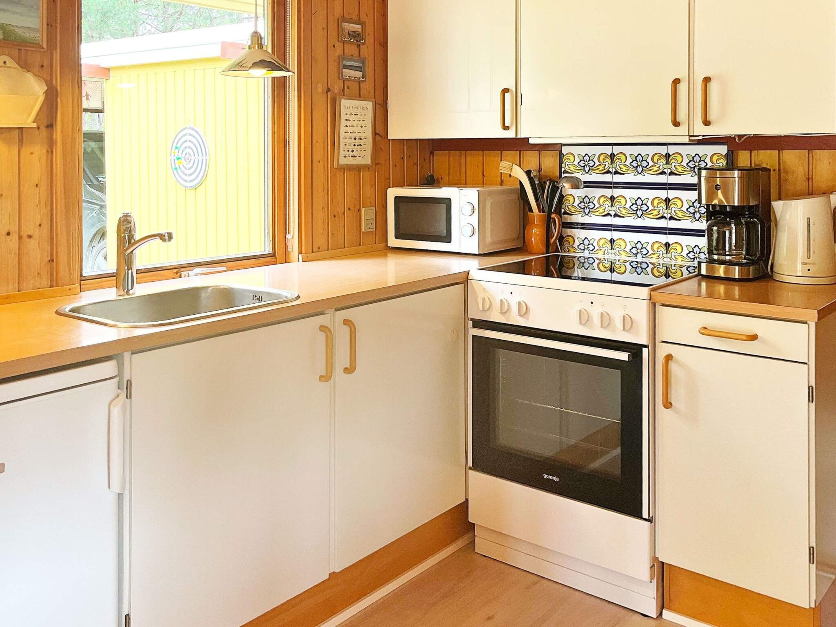 A kitchen with white cabinets, a microwave, an oven, and a coffee maker.