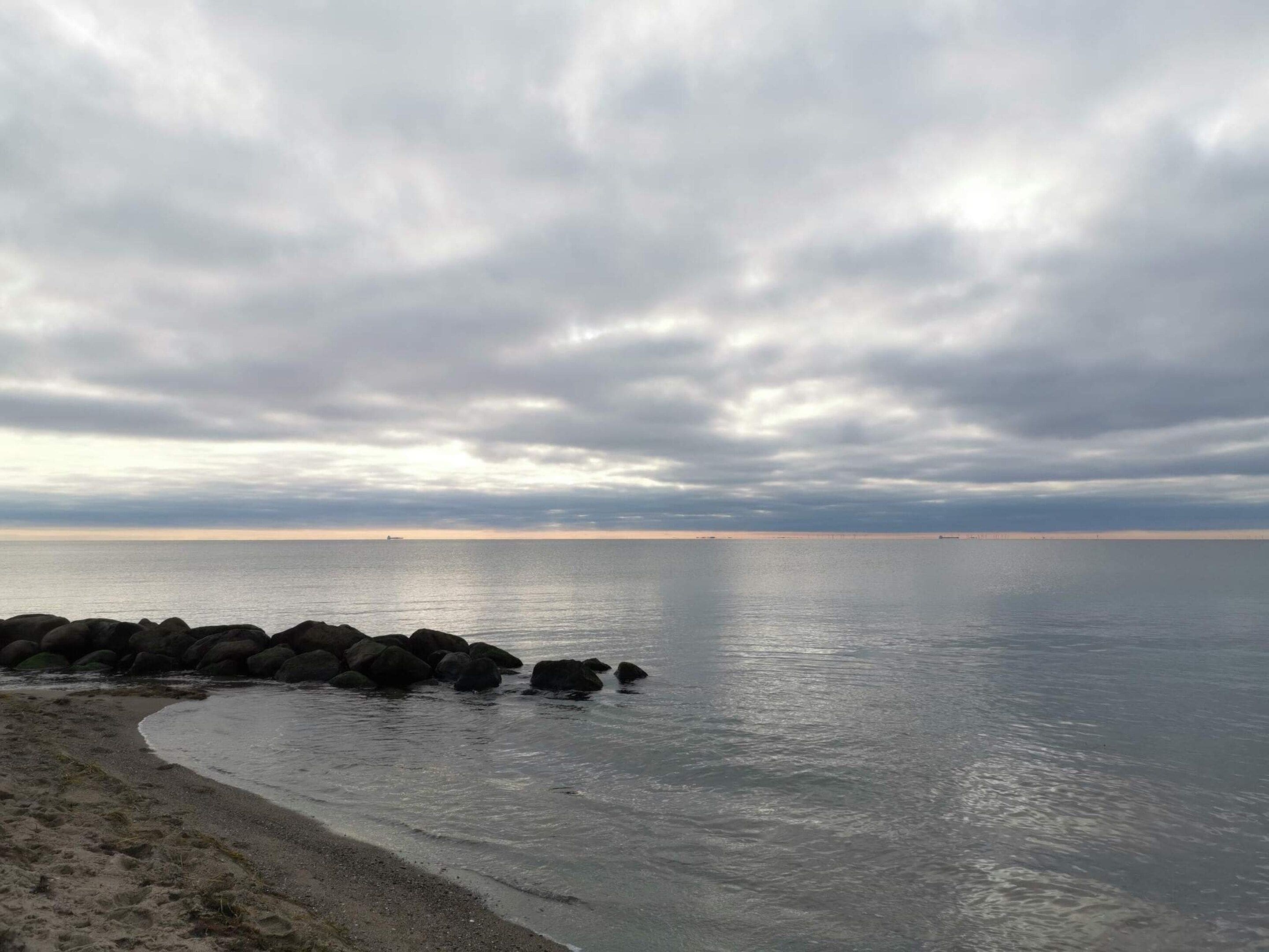 Ein Strand mit felsigem Ufer und ruhigem Wasser.