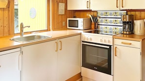 Eine kleine Küche mit weißen Schränken, einer Mikrowelle, einem Backofen und einer Kaffeemaschine.