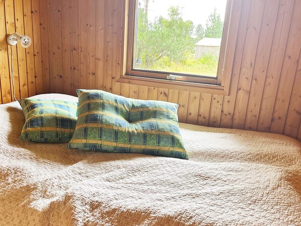 A bedroom with a large window, wooden walls, and a bed with two pillows. - 4 Person Holiday Home in Rodby (Rodby)