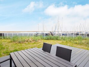 A wooden deck with two chairs and a table, overlooking a marina with boats. - Holiday Home in Wendtorf (Wendtorf)