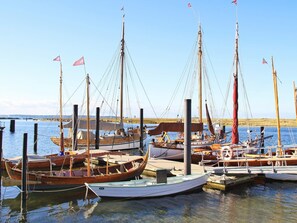 A marina with multiple wooden boats docked at wooden piers. - Holiday Home in Wendtorf (Wendtorf)