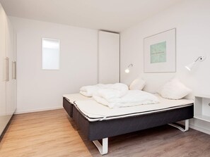 A modern bedroom with a bed, white walls, and a framed picture. - Holiday Home in Wendtorf (Wendtorf)