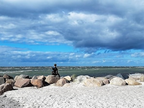 A rocky beach with a person standing on the rocks, overlooking the sea.