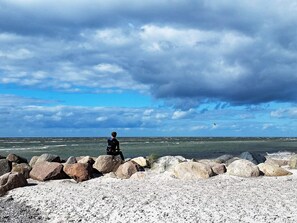 Una costa rocosa con una persona de pie sobre las rocas, mirando el mar.