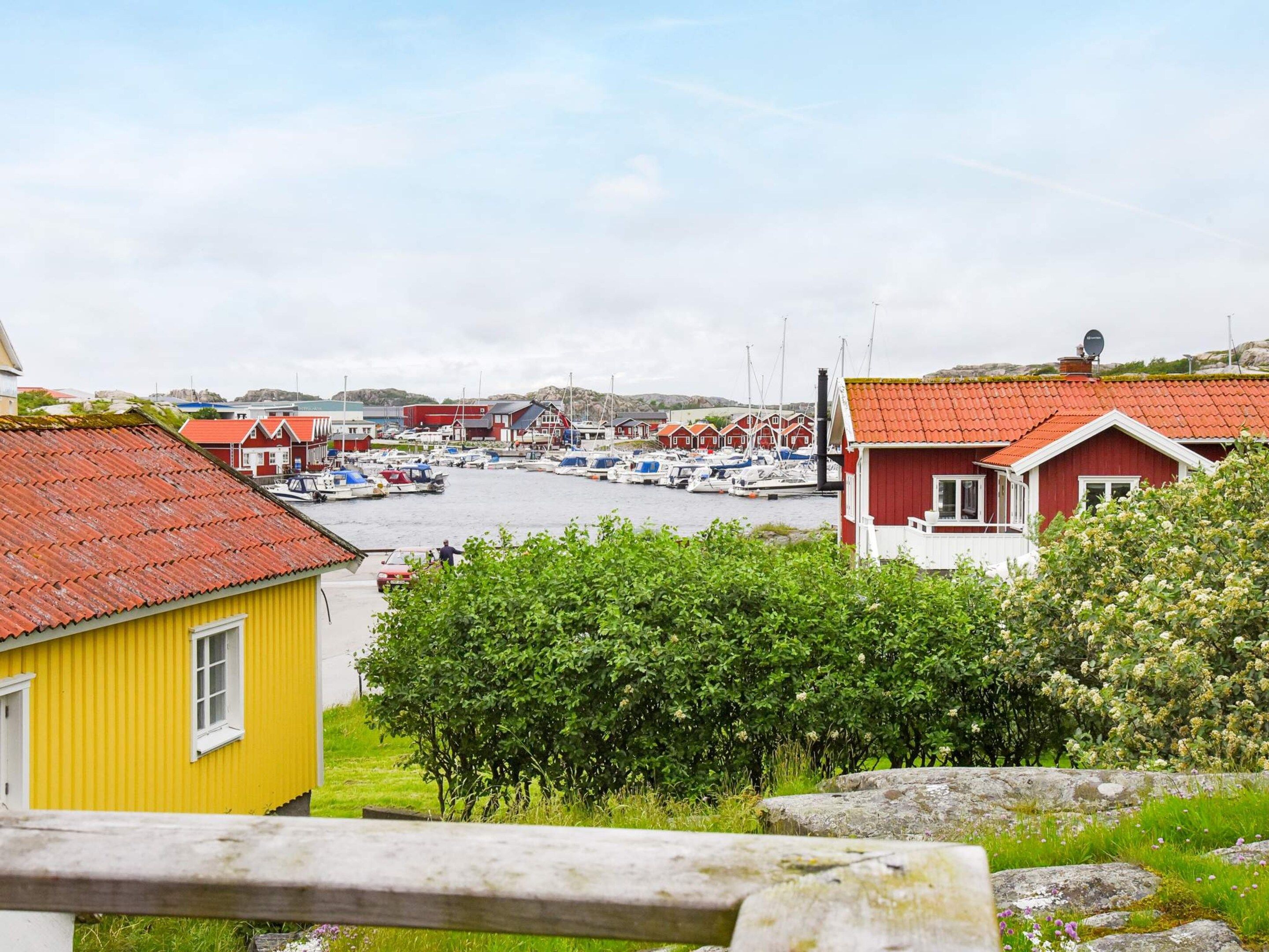 A coastal village with traditional red-roofed houses, a marina with boats, and a yellow building in the foreground.