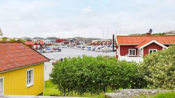 Un pueblo costero con casas tradicionales de techo rojo, un puerto deportivo con barcos y un edificio amarillo en primer plano.
