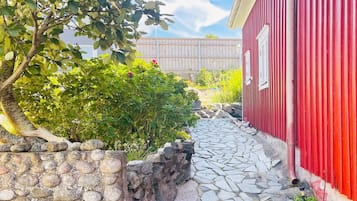 Un sendero de piedra que conduce a un edificio rojo, con una valla de madera al fondo.