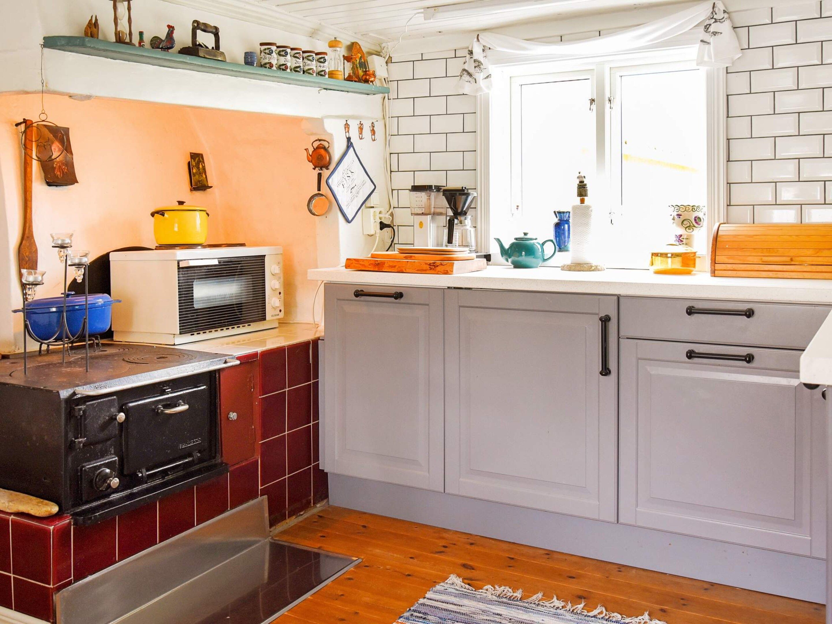 Una cocina con estufa, microondas y diversos utensilios sobre la encimera.