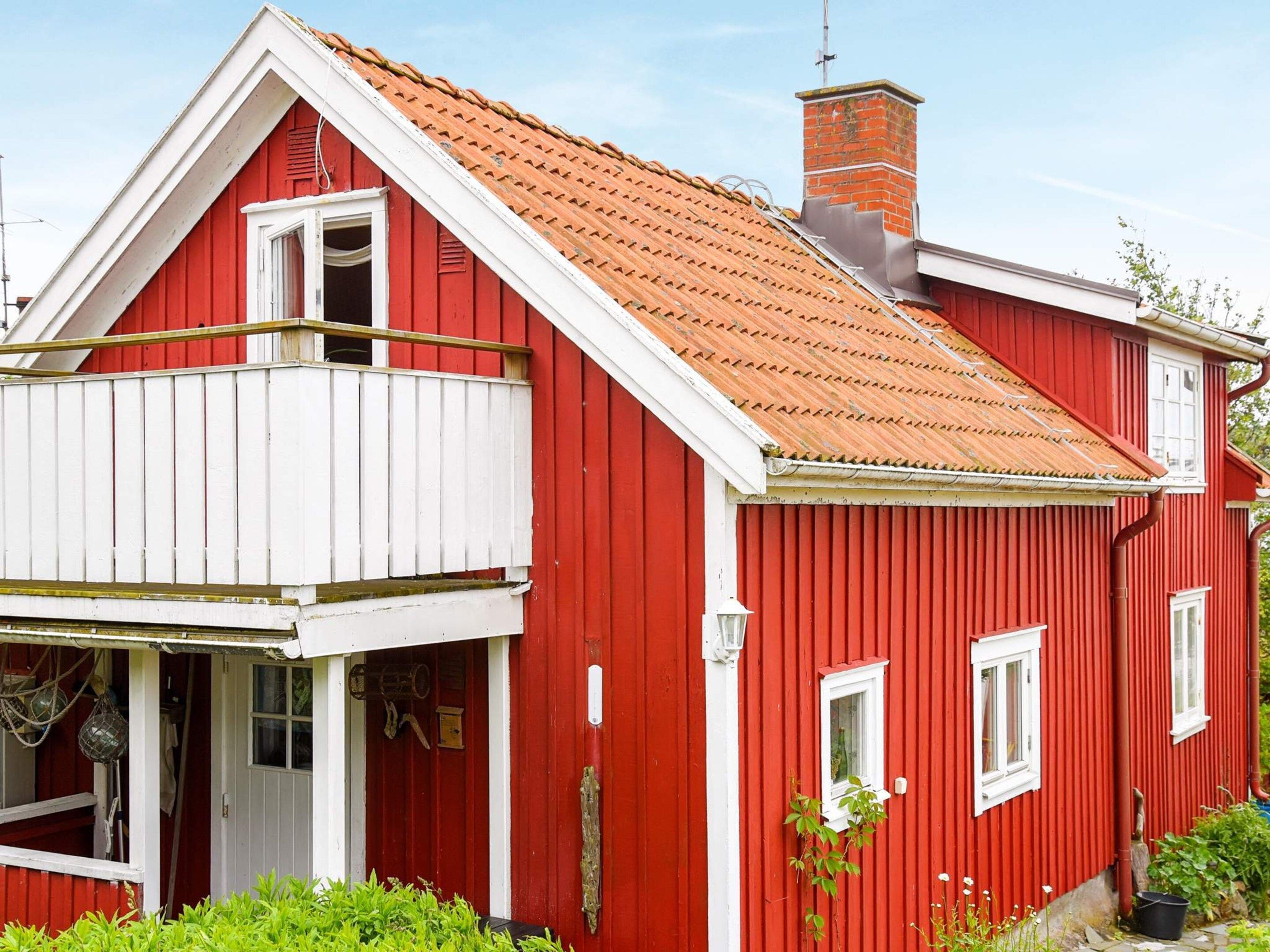 A red house with a white balcony, a chimney, and a window.