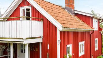 A red house with a white balcony, a chimney, and a window.