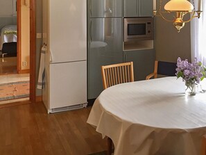A dining area with a table, chairs, a refrigerator, a microwave, and a vase with flowers. - Holiday Home in Vara (Vara)