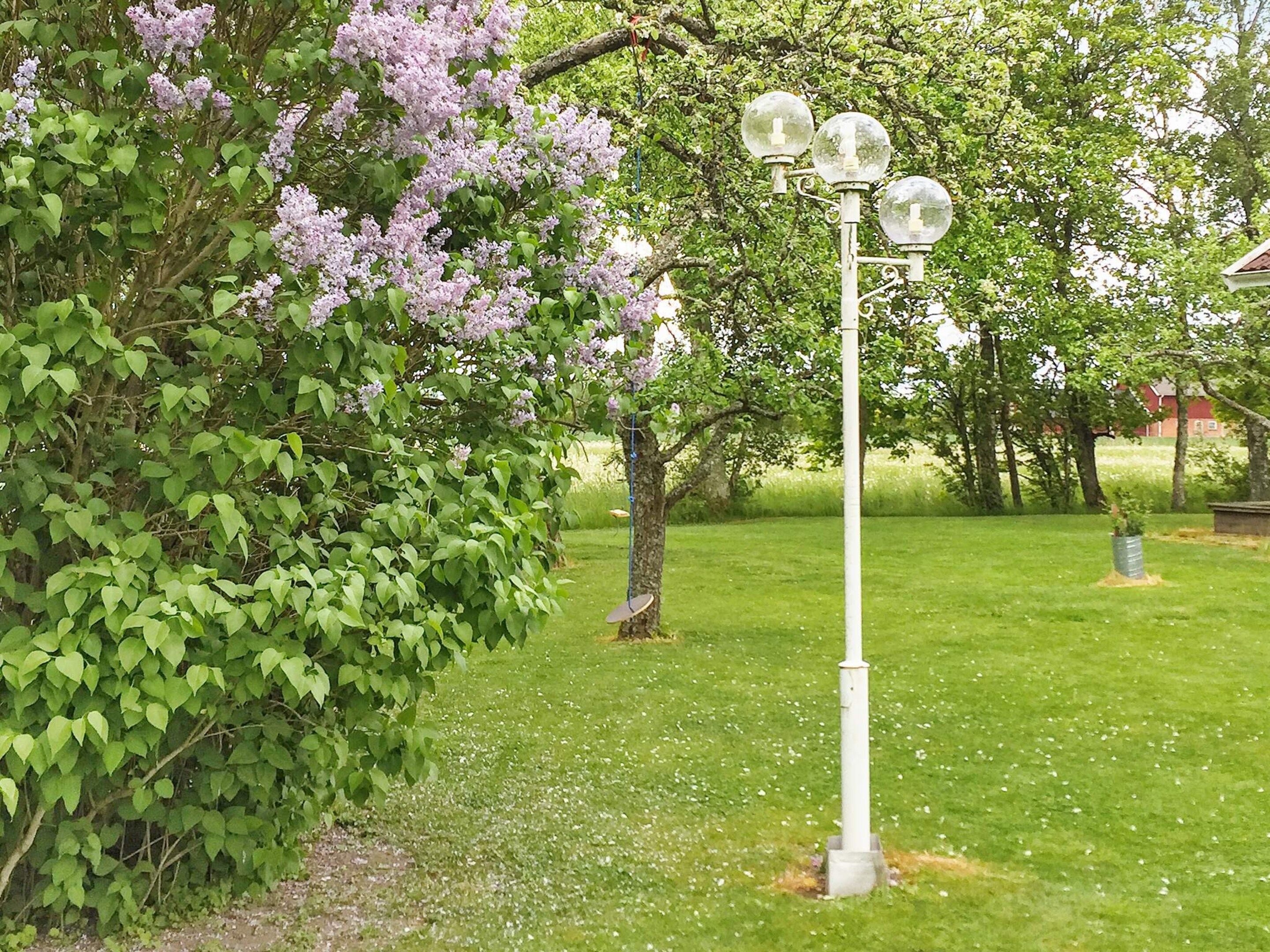 A garden with a white lamp post and a tree with purple flowers.