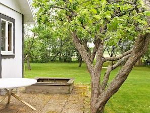 A garden with a wooden table and bench, a tree, and a grassy lawn. - Holiday Home in Vara (Vara)