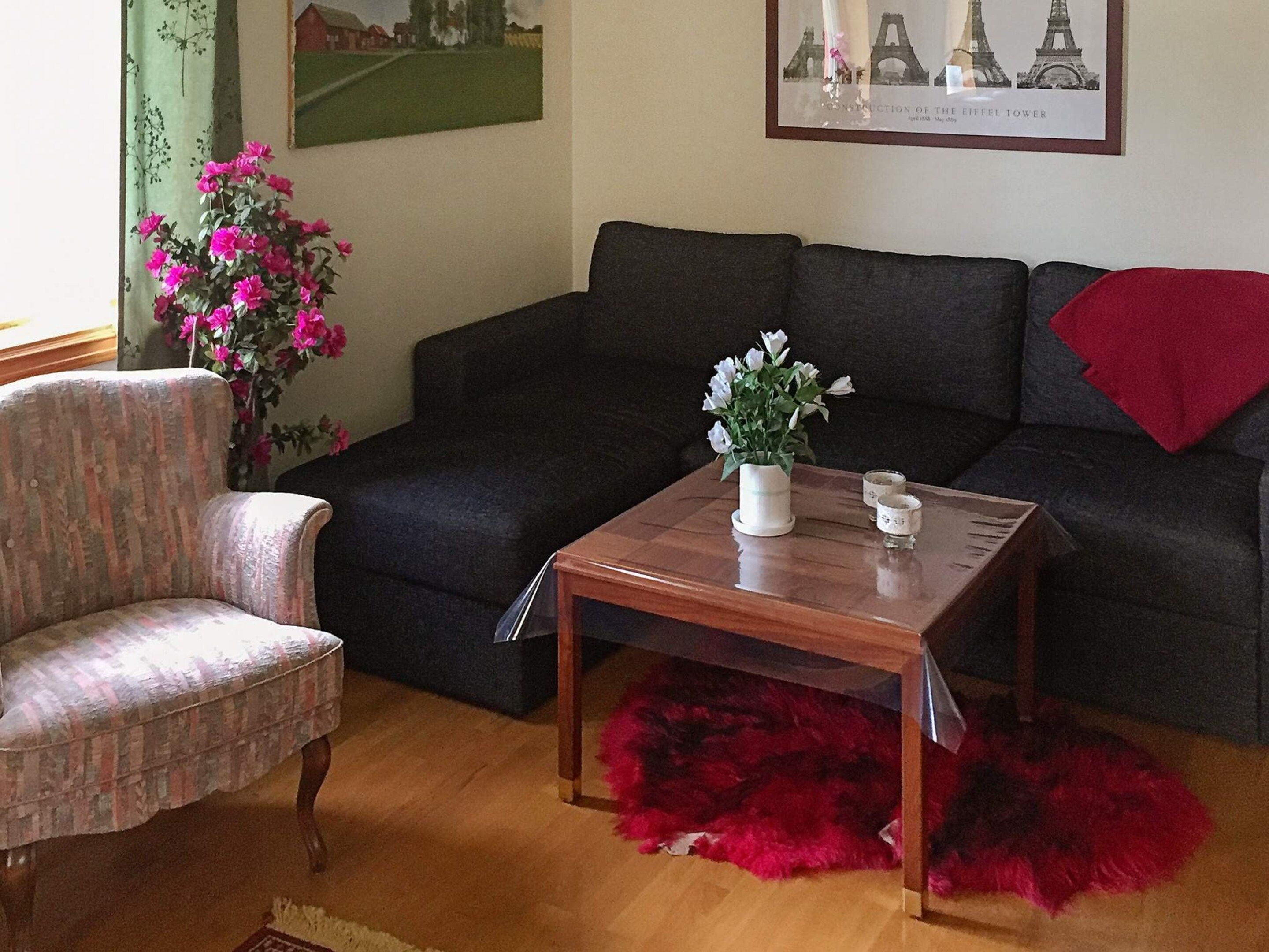 Una sala de estar con sofá, sillón, mesa de centro y un cuadro de la Torre Eiffel.