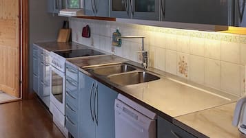 A kitchen with a dishwasher, double sink, and wooden cabinets.