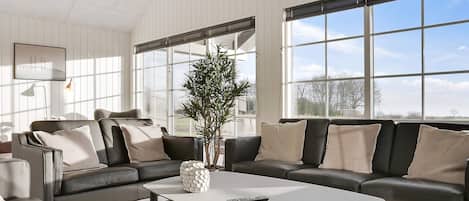 A modern living room with a sectional sofa, a coffee table, and a potted plant.
