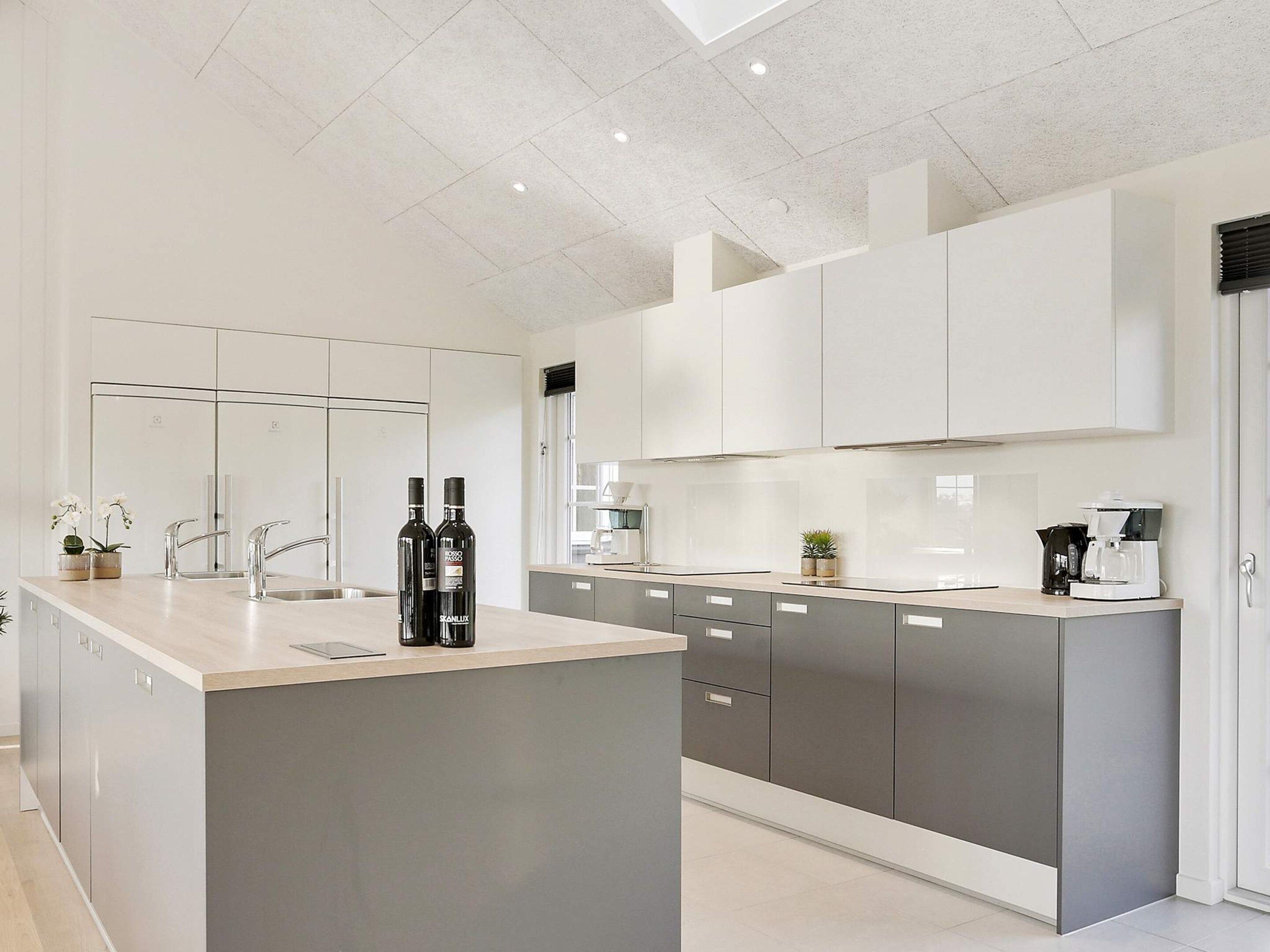 Una cocina moderna con una isla central, armarios grises y encimera blanca.