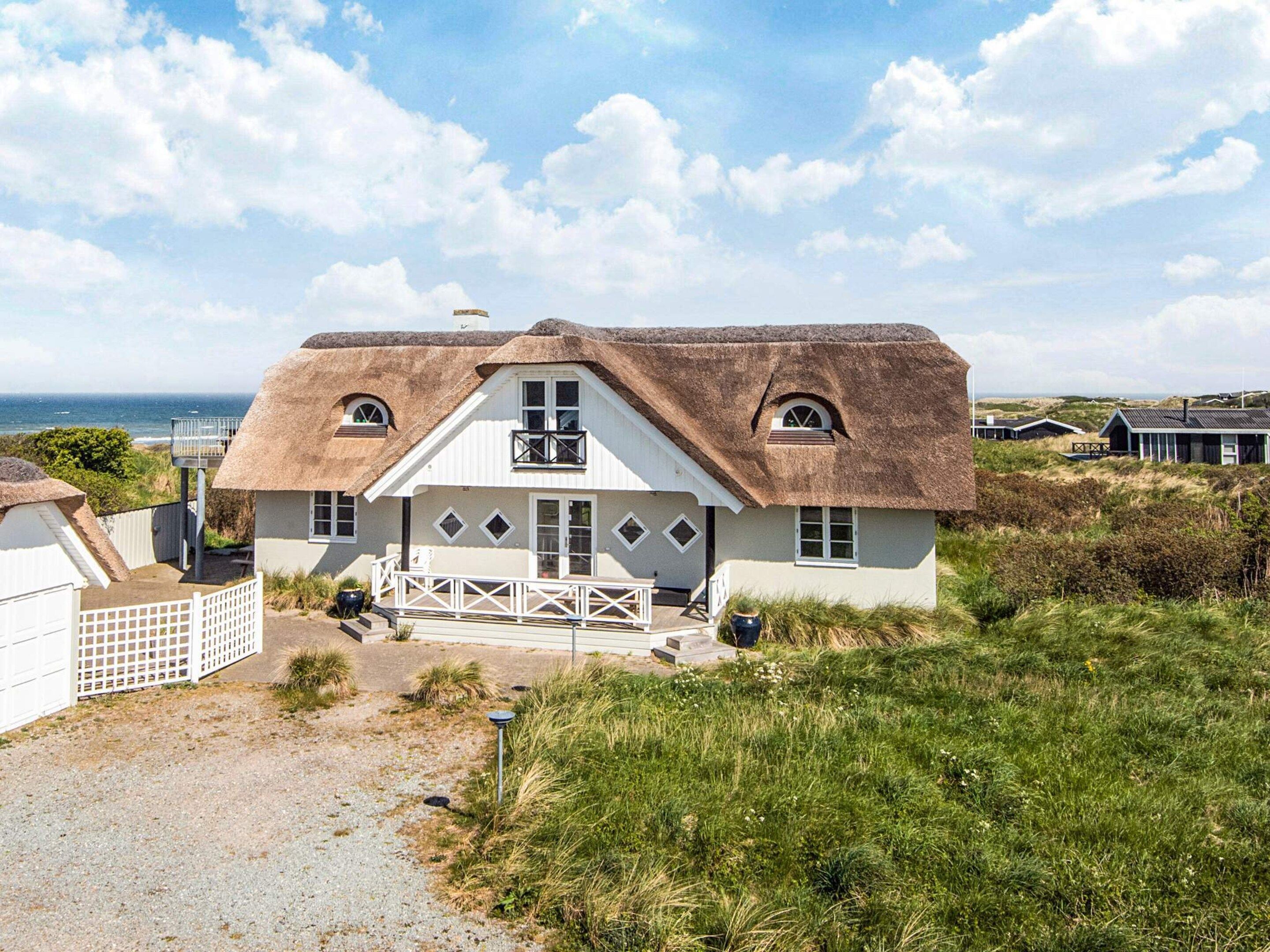 Ett hus vid kusten med ett halmtak, en balkong och utsikt över havet.