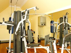 Une salle de sport équipée de divers appareils d’exercice, d’un sac de frappe et d’un climatiseur fixé au mur.
