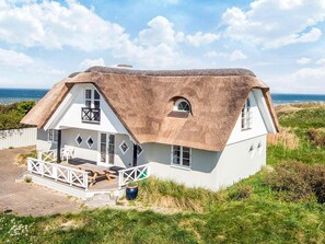 A thatched-roof house with a balcony, a small garden, and a view of the sea. - 4 Star Holiday Home in Hirtshals (Hirtshals)